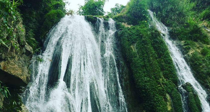 The waterfall is outstanding among green mountains and forests